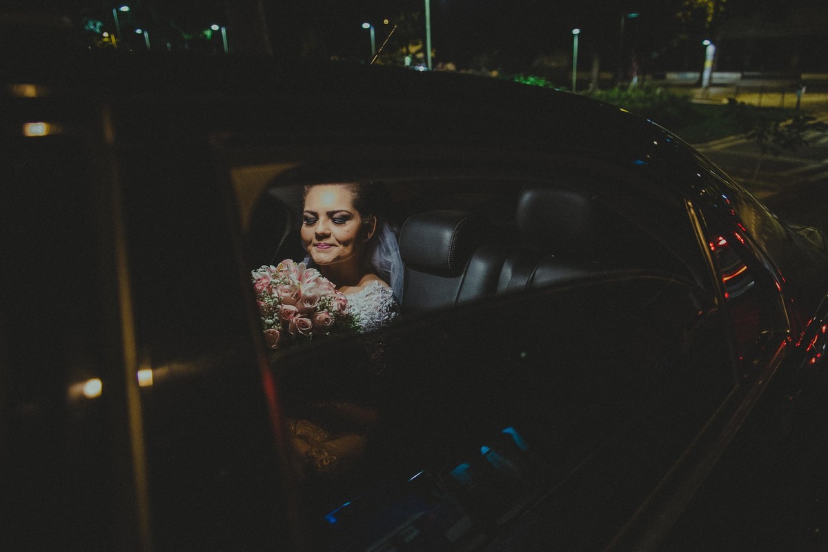 Noiva dentro do uber esperando a hora de entrar no seu casamento na igreja da Boa Viagem em Belo Horizonte segurando seu buque e olhando para ele