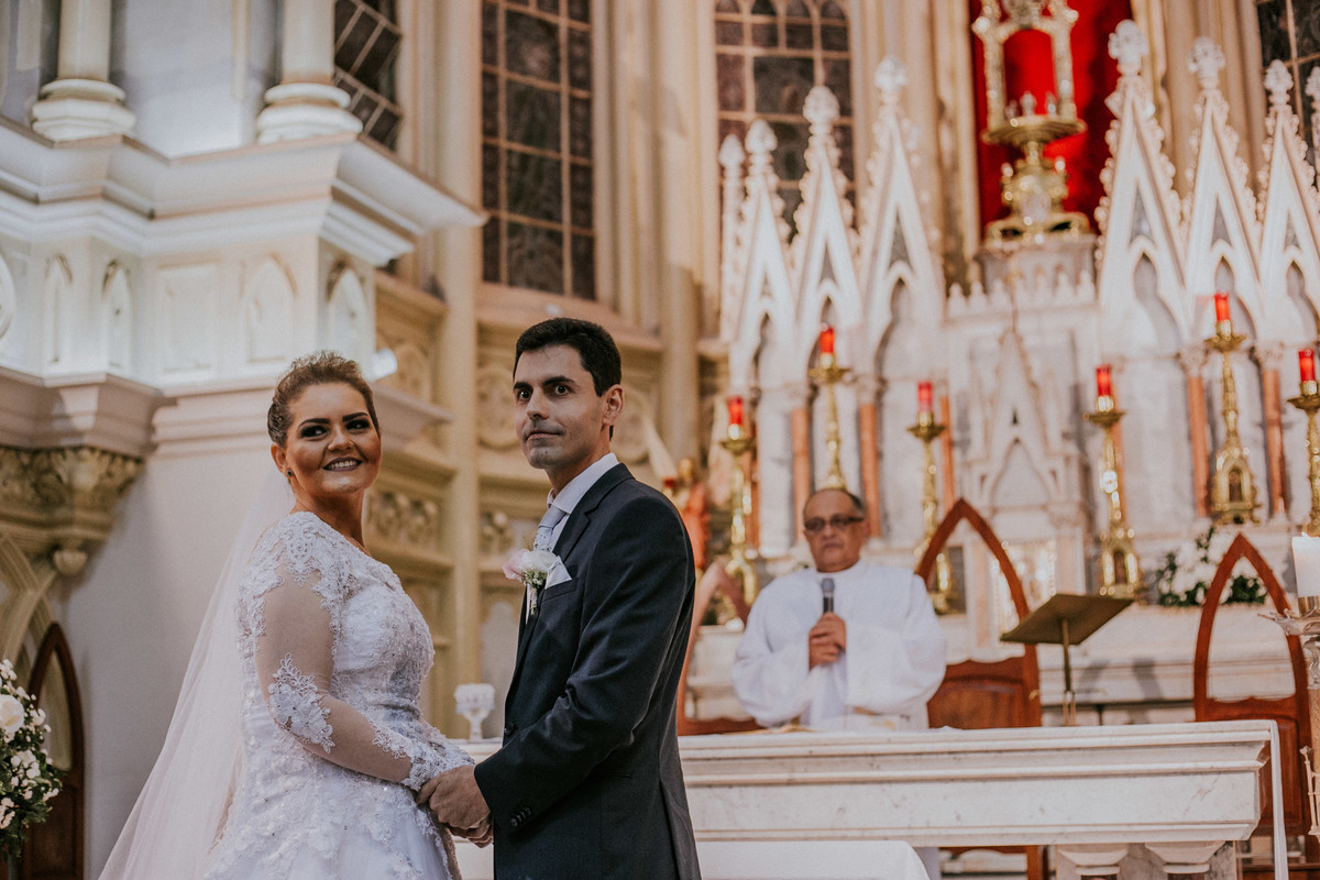 Noivos de mãos dadas no altar da igreja da boa viagem e sorrindo
