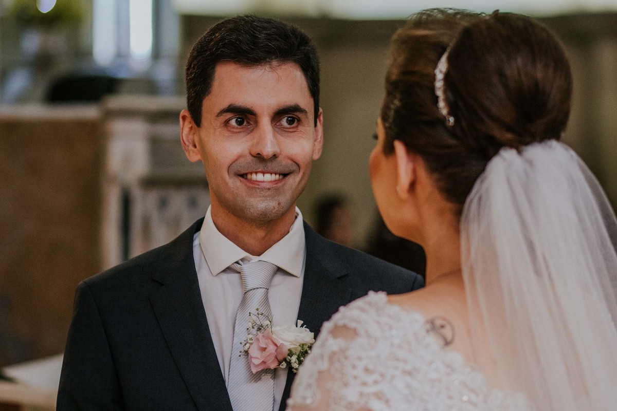 Noivo sorrindo para a noiva ao escutar seus votos