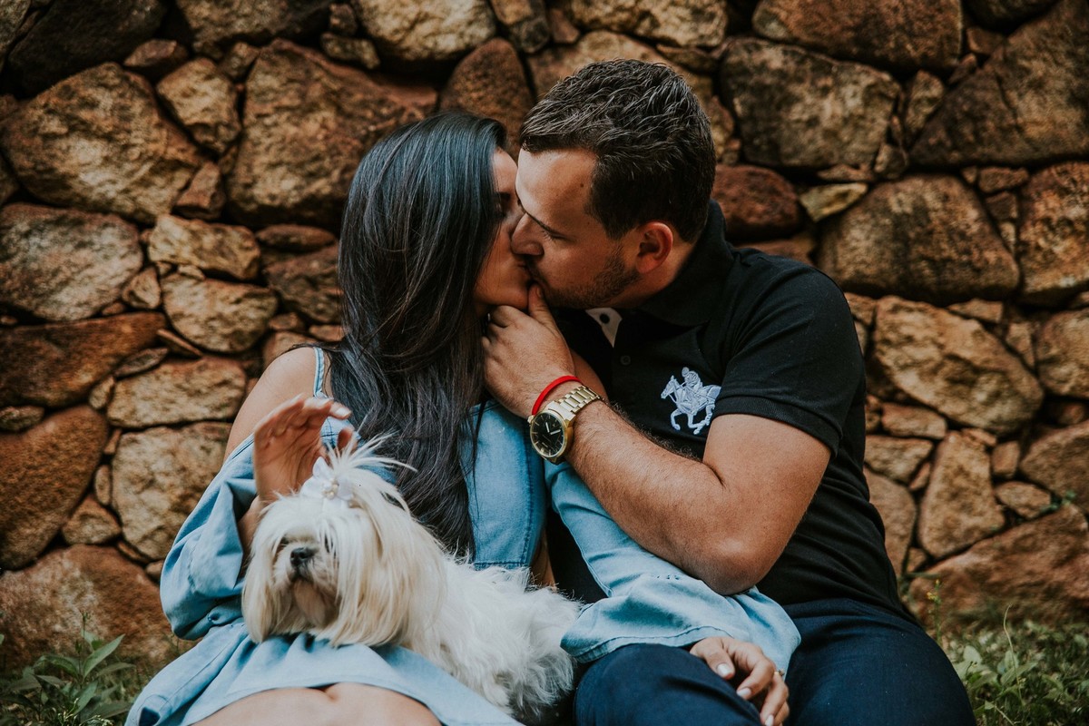 noivos se beijando durante um ensaio de pré casamento com bicho de estimação em casa branca
