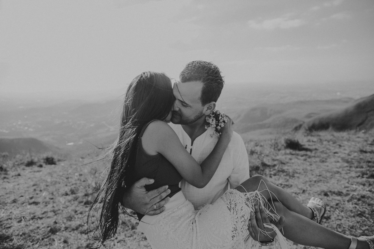 Noivo carregando a noiva no colo e a beijando em um ensaio de pré casamento na serra do rola moça