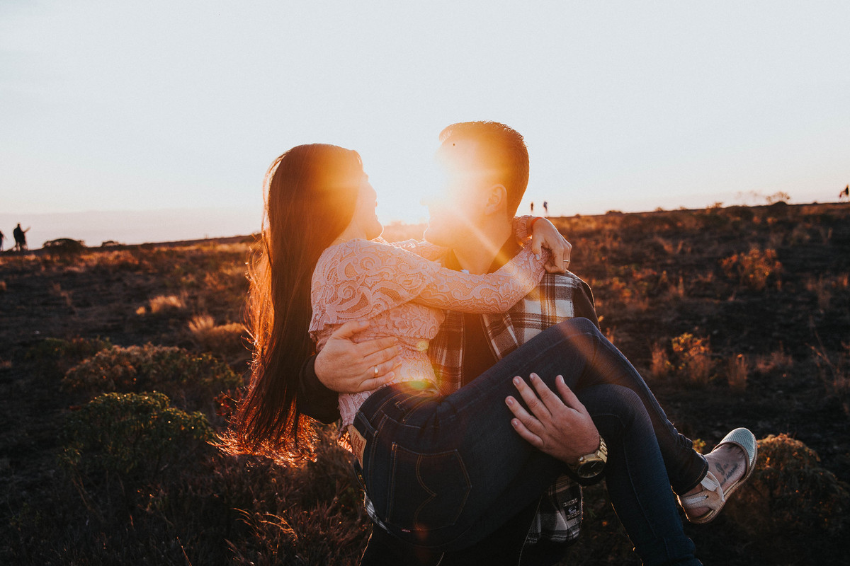 Noivo carregando a noiva no colo no por do sol durante um ensaio de pré casamento na serra do rola moça em Belo Horizonte