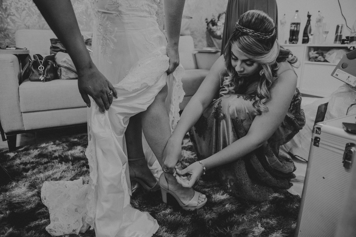 Irma da noiva ajudando a noiva a calçar o sapato antes da cerimonia de casamento