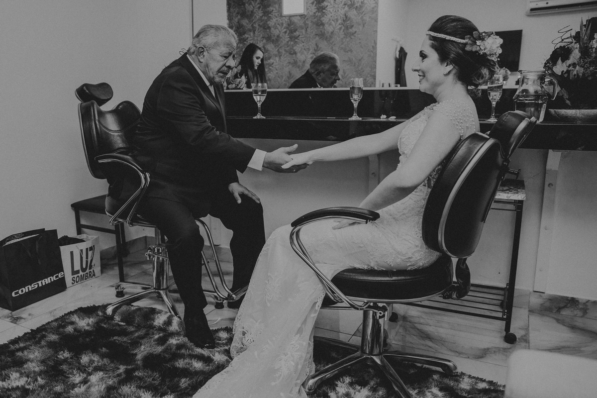 Pai da noiva segurando as mãos dela antes do casamento