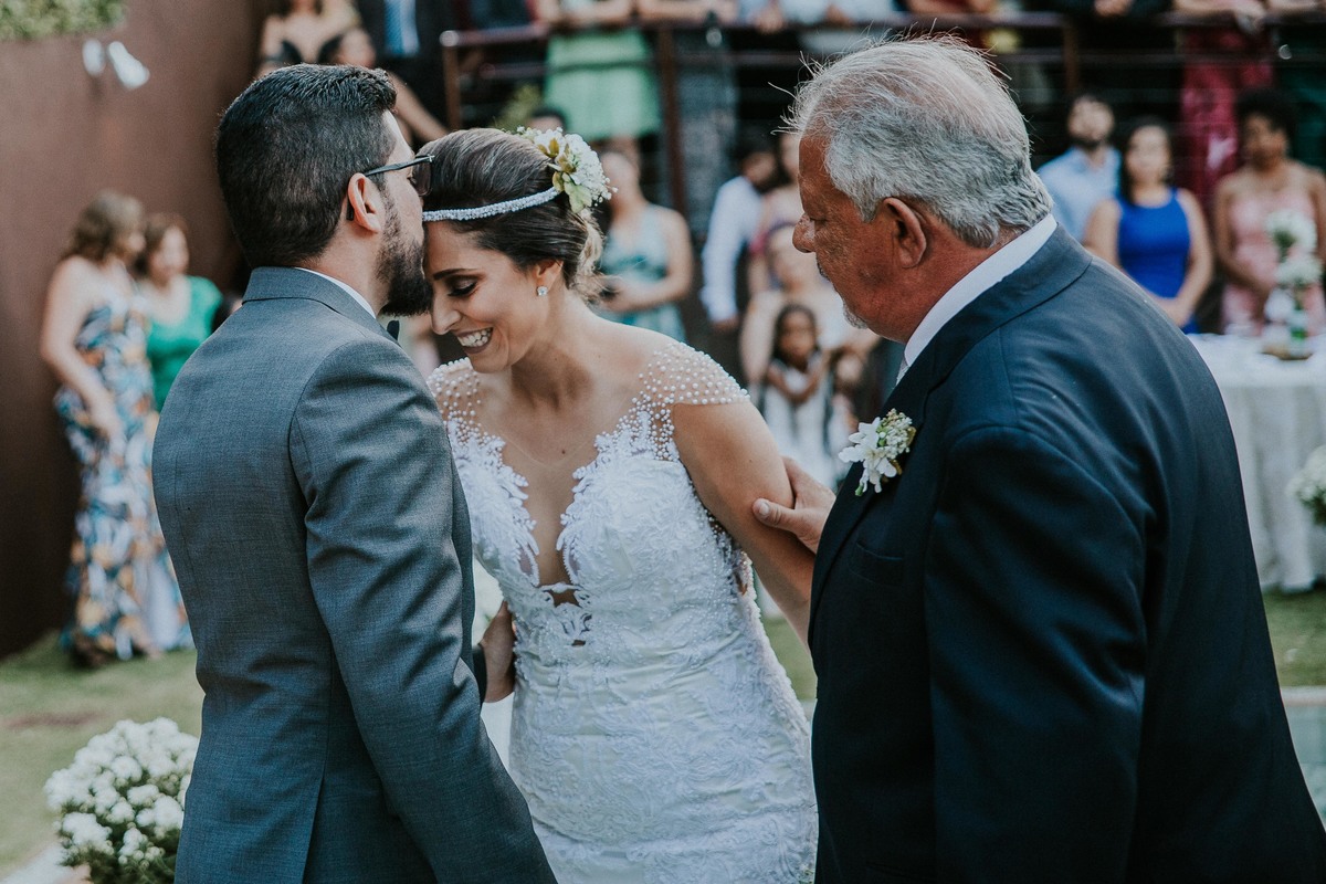 noivo dando um beijo na testa da noiva ao recebe-la do pai da noiva durante a cerimonia de casamento durante o dia na Pampulha