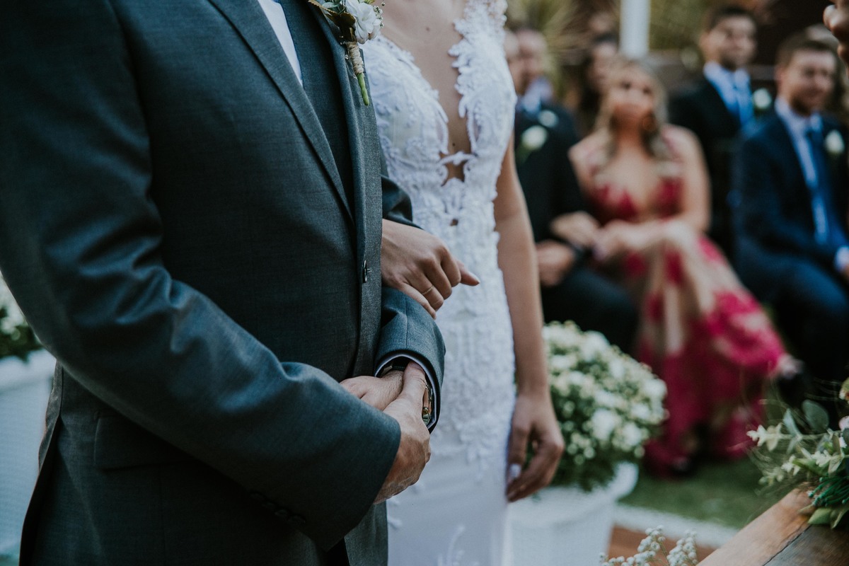 detalhe dos noivos de braços dados durante a cerimonia de casamento
