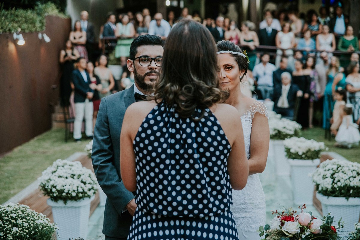 Casamento durante o dia em Belo Horizonte em que os noivos estão olhando para a celembrante