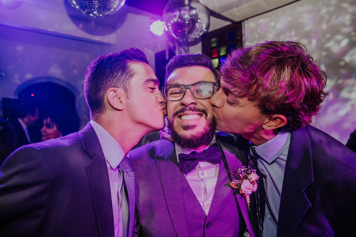 padrinhos beijando o rosto do noivo durante a recepção de casamento em BH