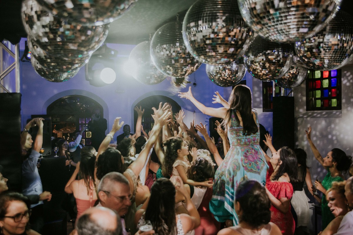 Noiva jogando o buque enquanto uma convidada esta de cavalinho nas costas de outra