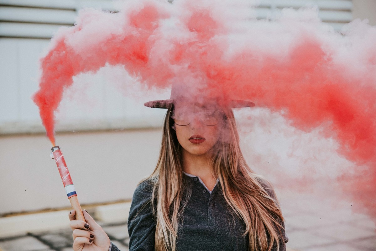 ensaio feminino criativo em betim do qual a modelo está segurando fumaça colorida