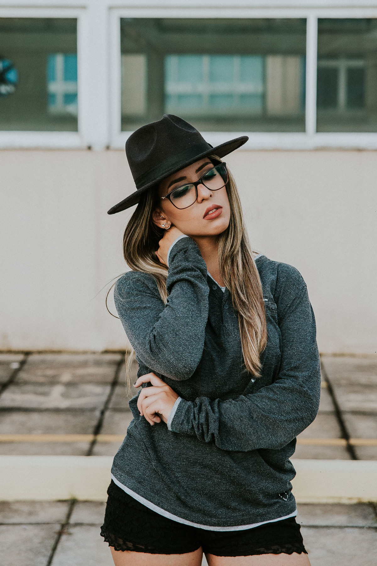 retrato feminino criativo no qual a modelo está com uma das mãos no pescoço e ao outra pelo corpo e usa um chapéu fedora
