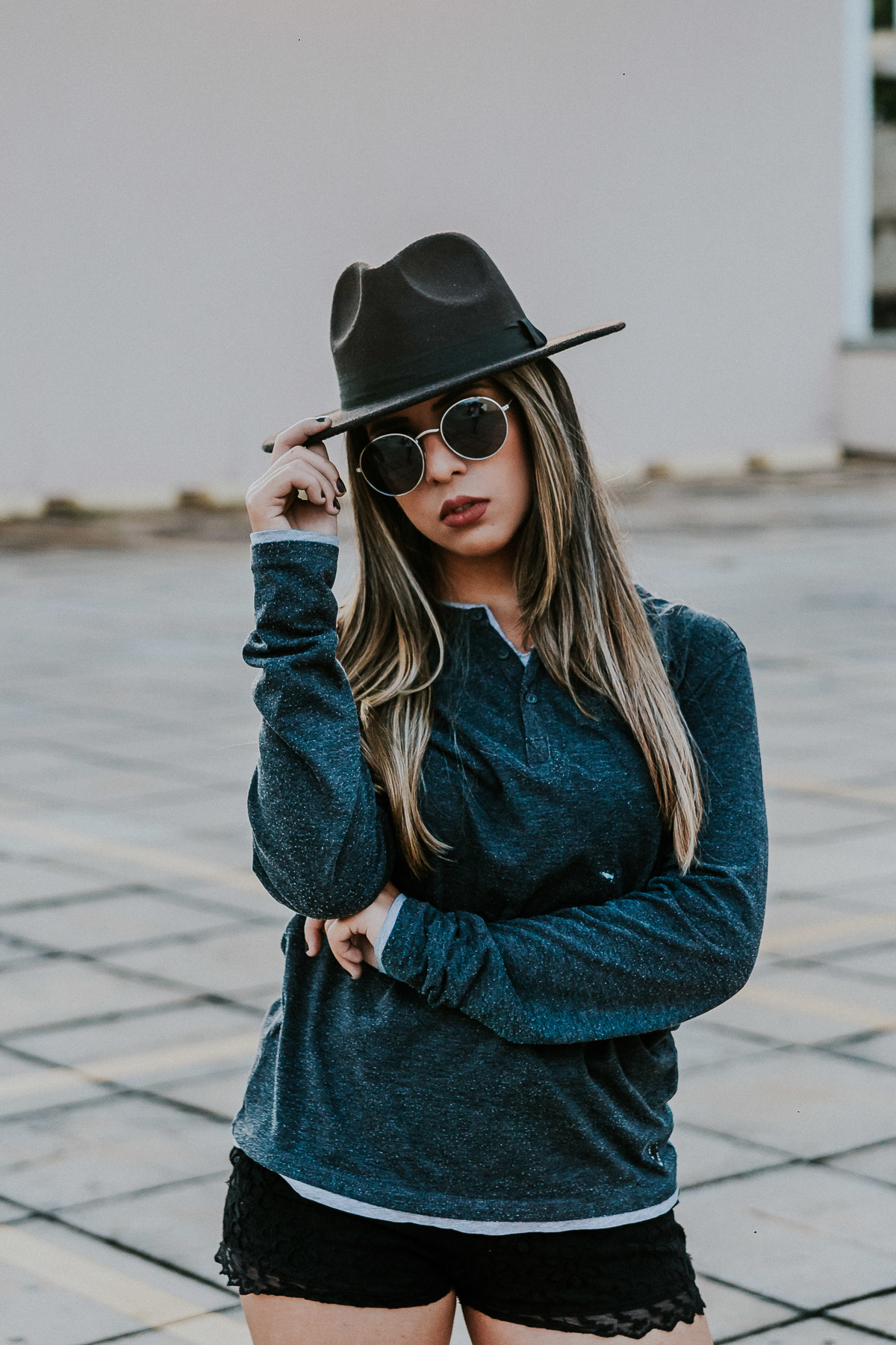 retrato feminino criativo no qual a modelo está usando oculos escuros e chapeu fedora
