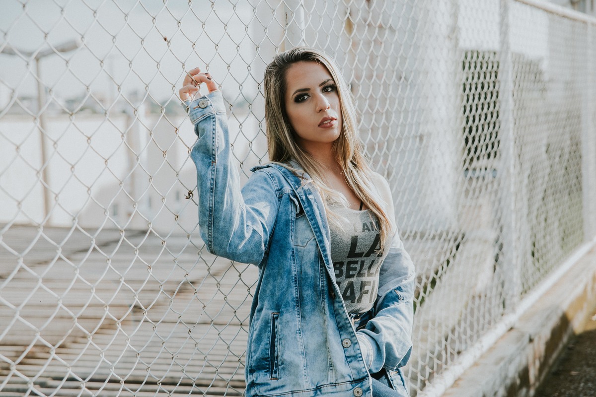 melhor fotografia de ensaio feminino em betim no qual a modelo está na frente de uma cerca proxima ao centro de betim