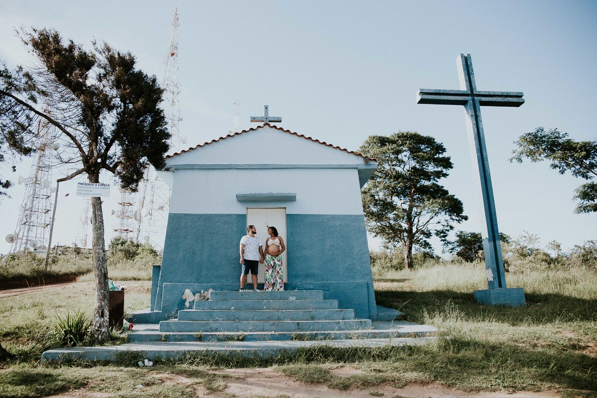 inspiração de fotografia de gestante no qual os pais estão na frente de uma capela na serra do elefante em mateus leme