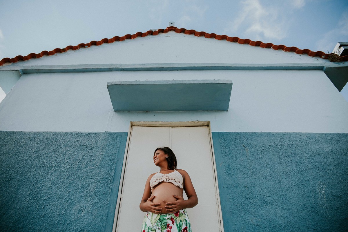 ensaio de gestante criativo no qual a mãe está na frente de uma igreja e segurando a barriga 