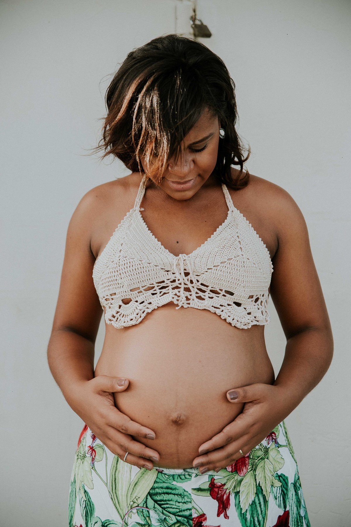 ensaio de gestante no qual a mãe está segurando a barriga em uma fotografia criativa
