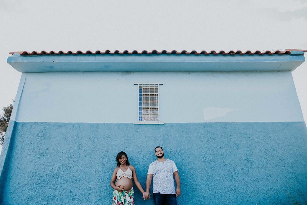 inspiração para ensaio de gestante no qual os pais estão na frente de uma parede azul de uma capela