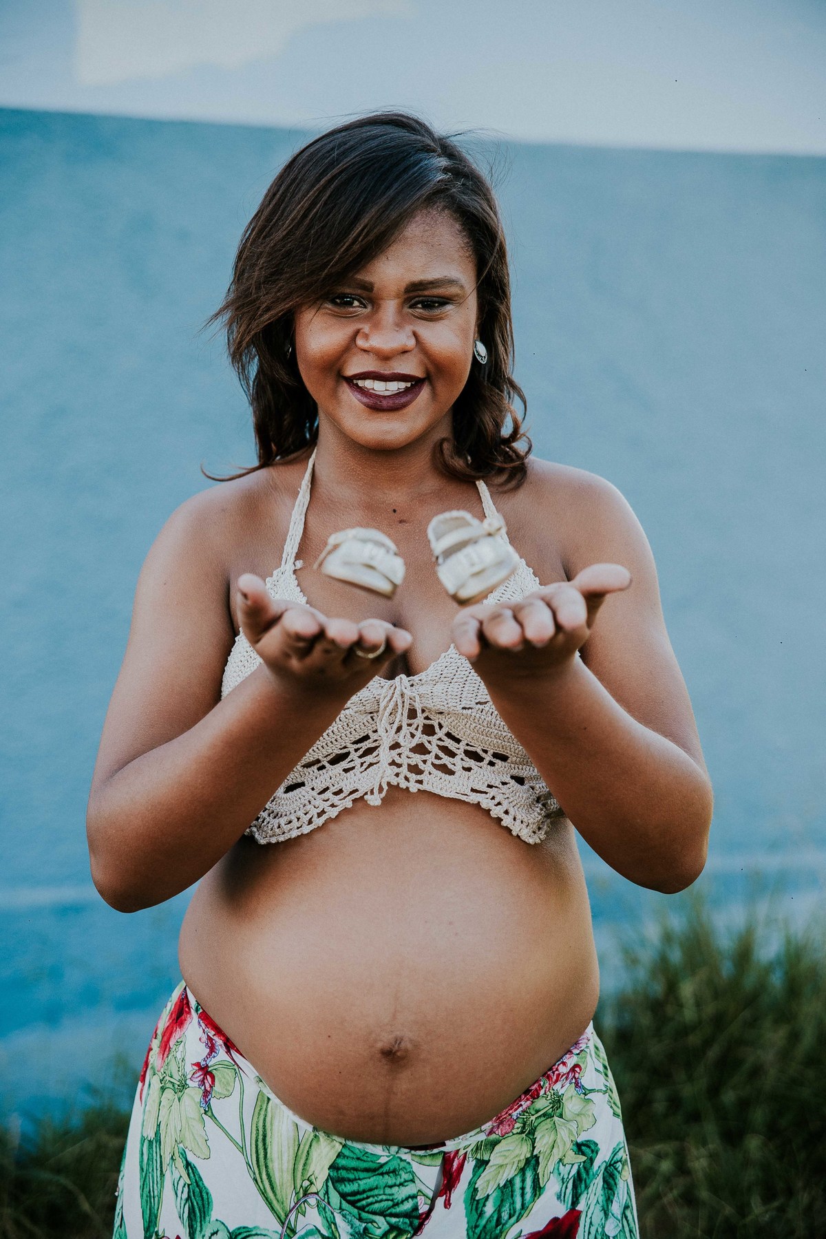 fotografia criativa de gestante no qual os sapatinhos do bebe estão voando