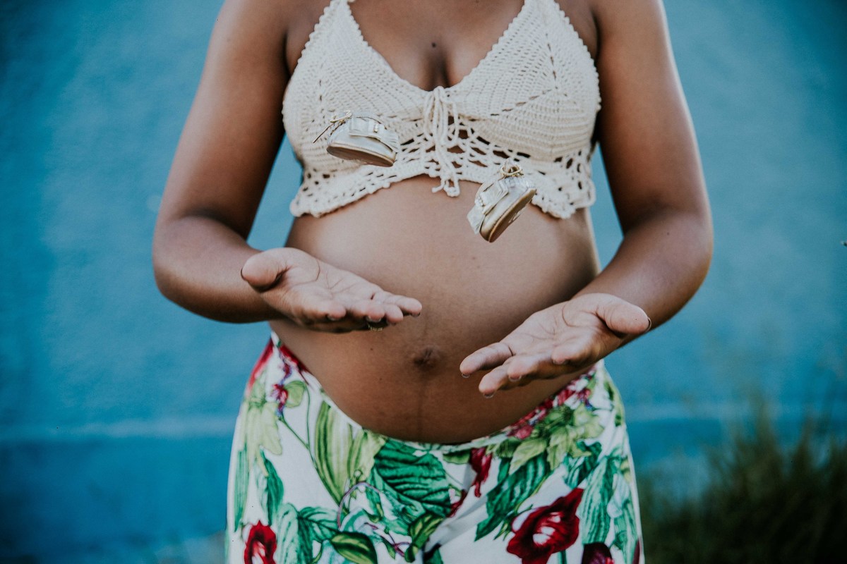 fotografia criativa de sapatinhos de bebe qual eles estão voando na frente da barriga da mãe