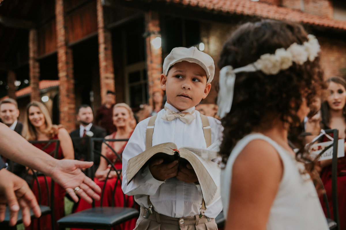 fotografia criativa do pagem com a biblia durante a entrada da cerimonia de casamento durante o dia