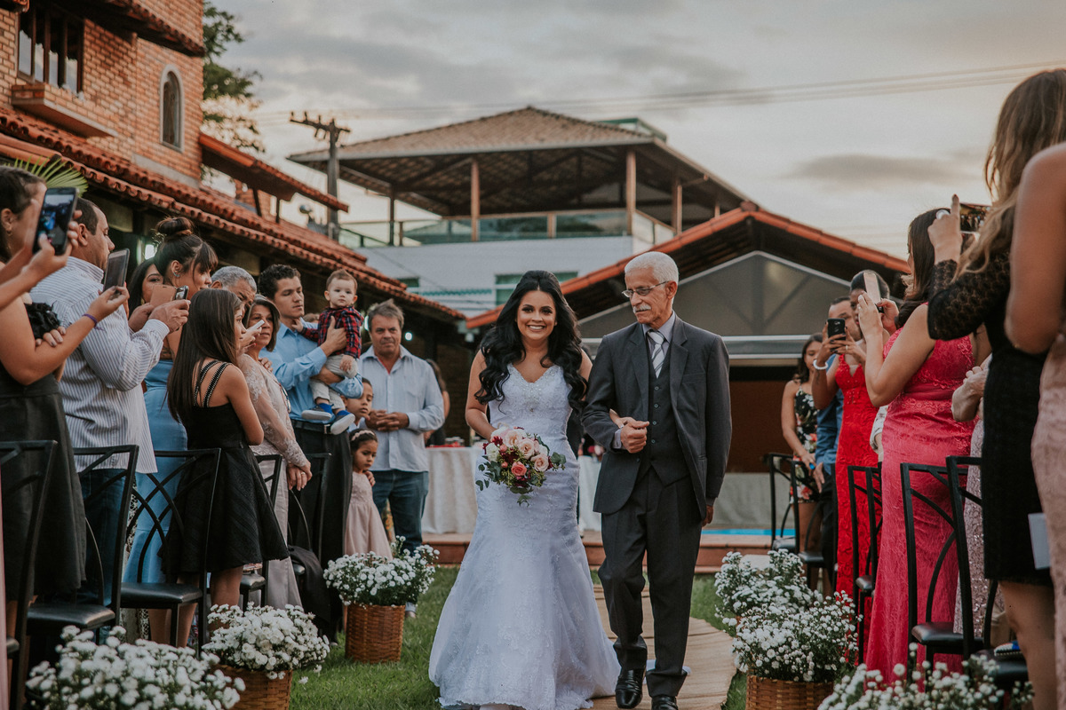 Fotografia de casamento em belo horizonte da entrada da noiva com o pai na cerimônia de casamento feita durante o dia 