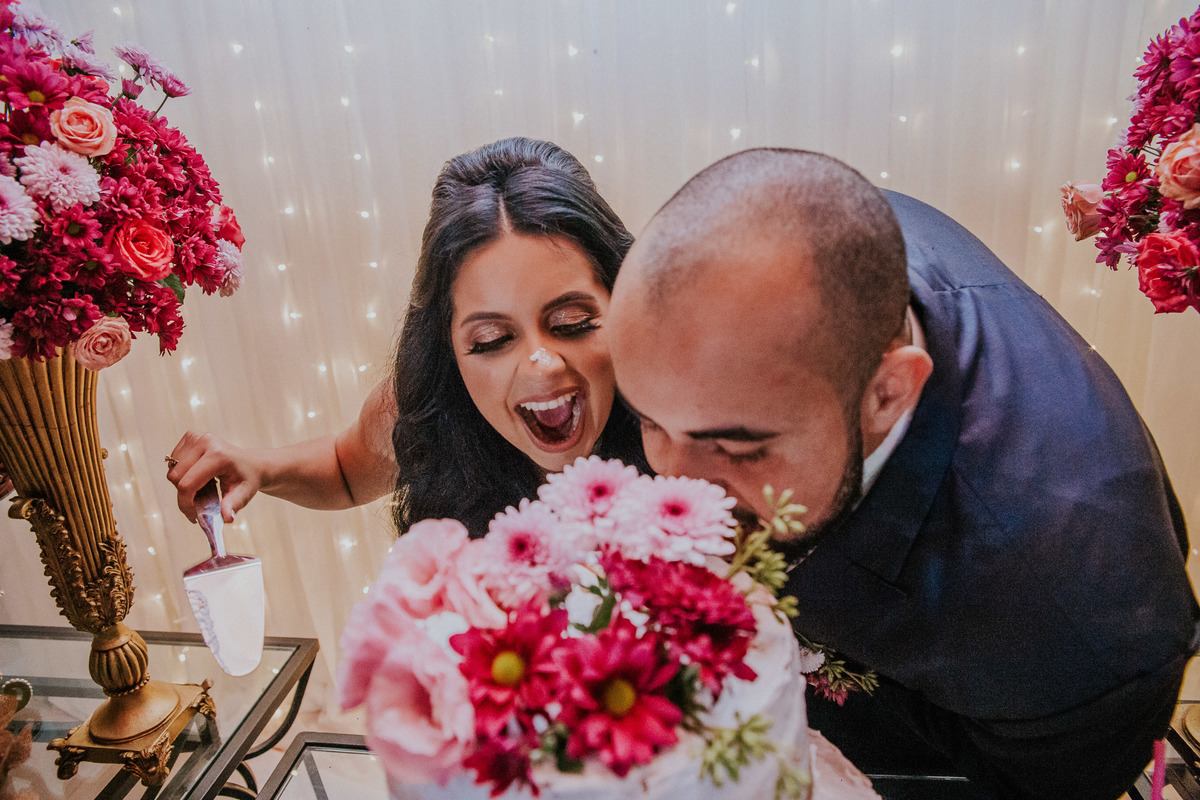 noivos se divertindo em uma fotografia criativa do corte do bolo de casamento
