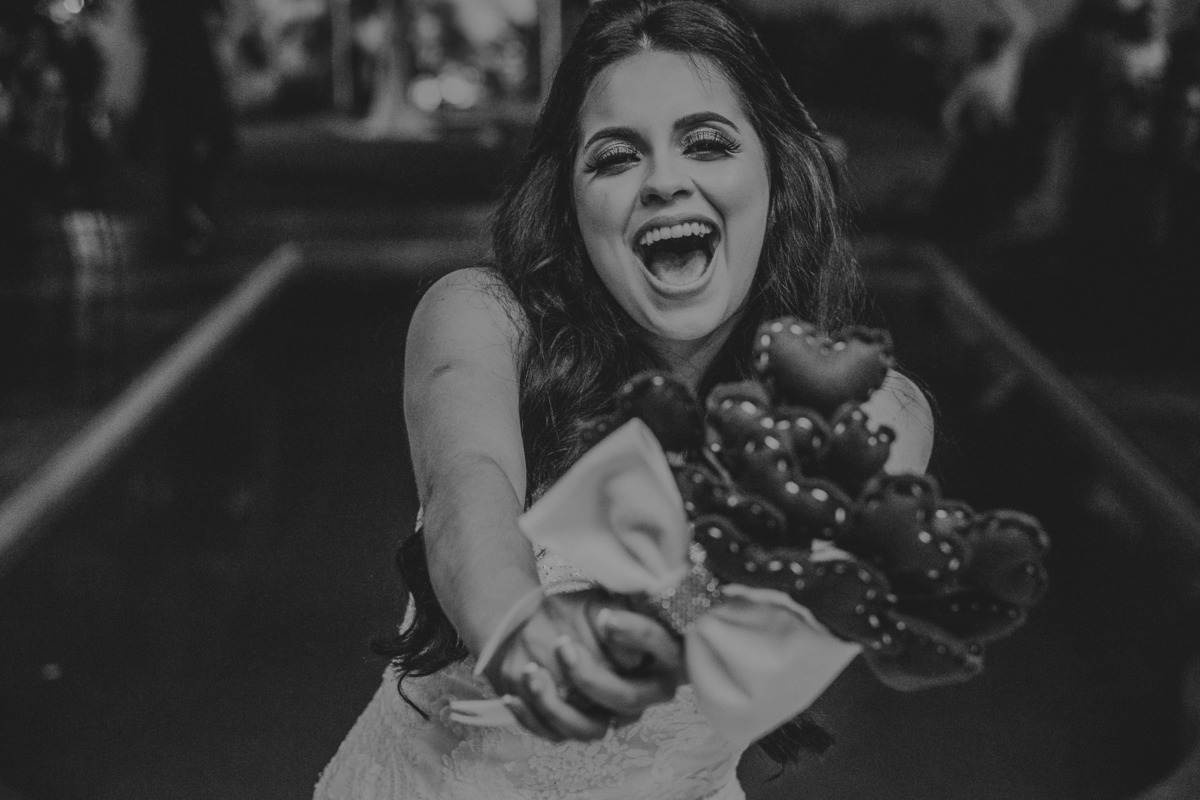 Noiva segurando o buque e sorrindo em uma fotografia criativa de casamento