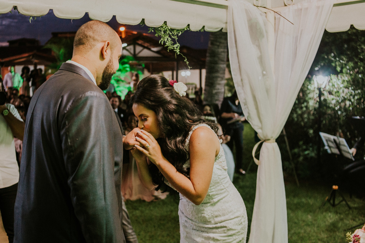 noiva beijando a mão do noivo após colocar a aliança no dedo dele