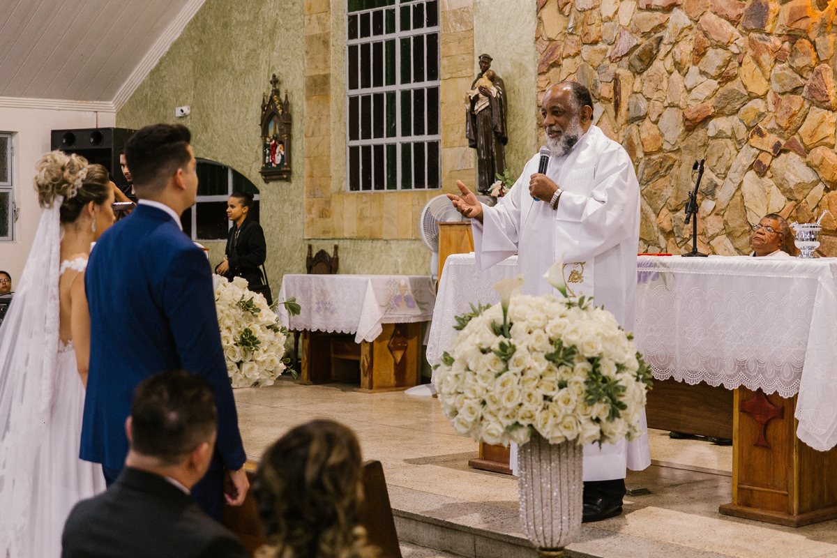 fotografia de casamento em santa luzia no qual o padre está falando com os noivos