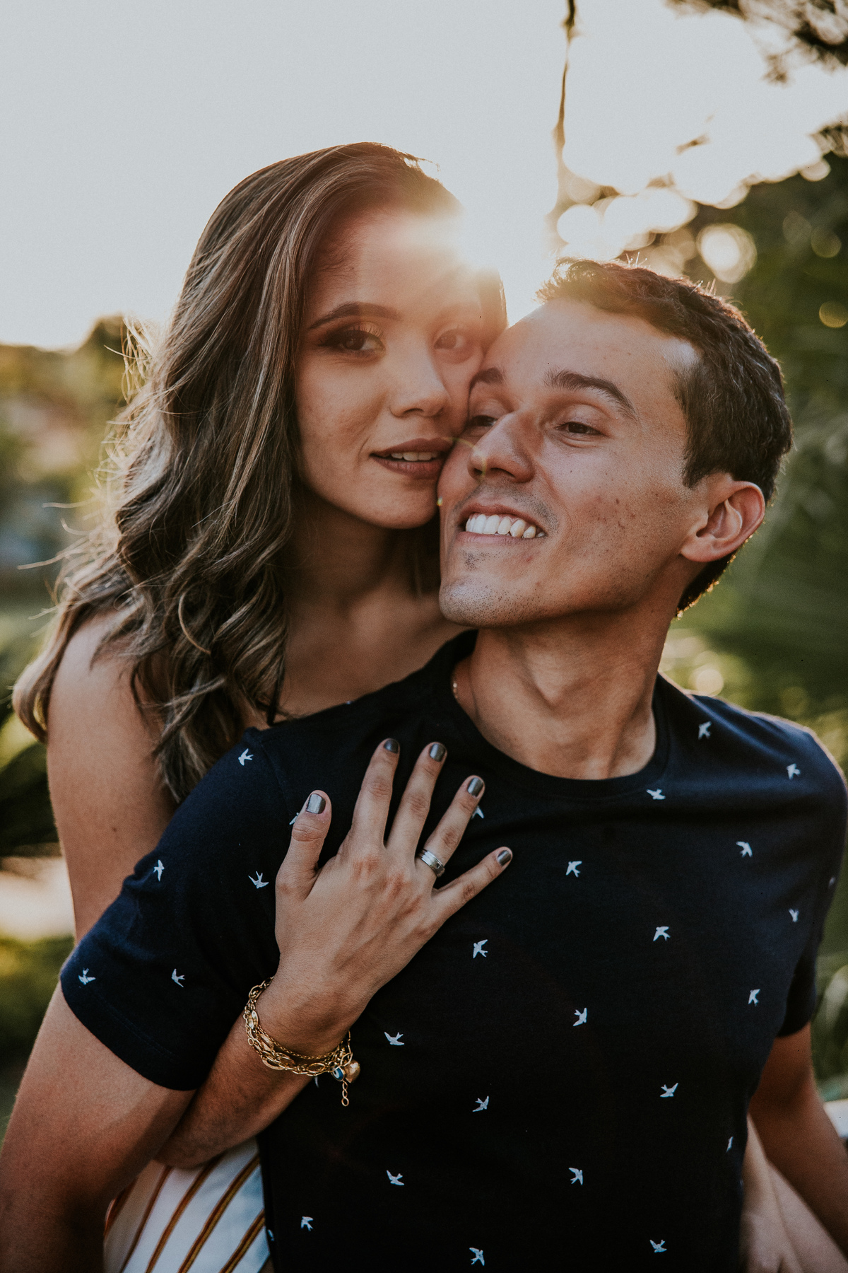 Fotografia espontânea de casal no qual os dois estão sorrindo um para o outro no por do sol