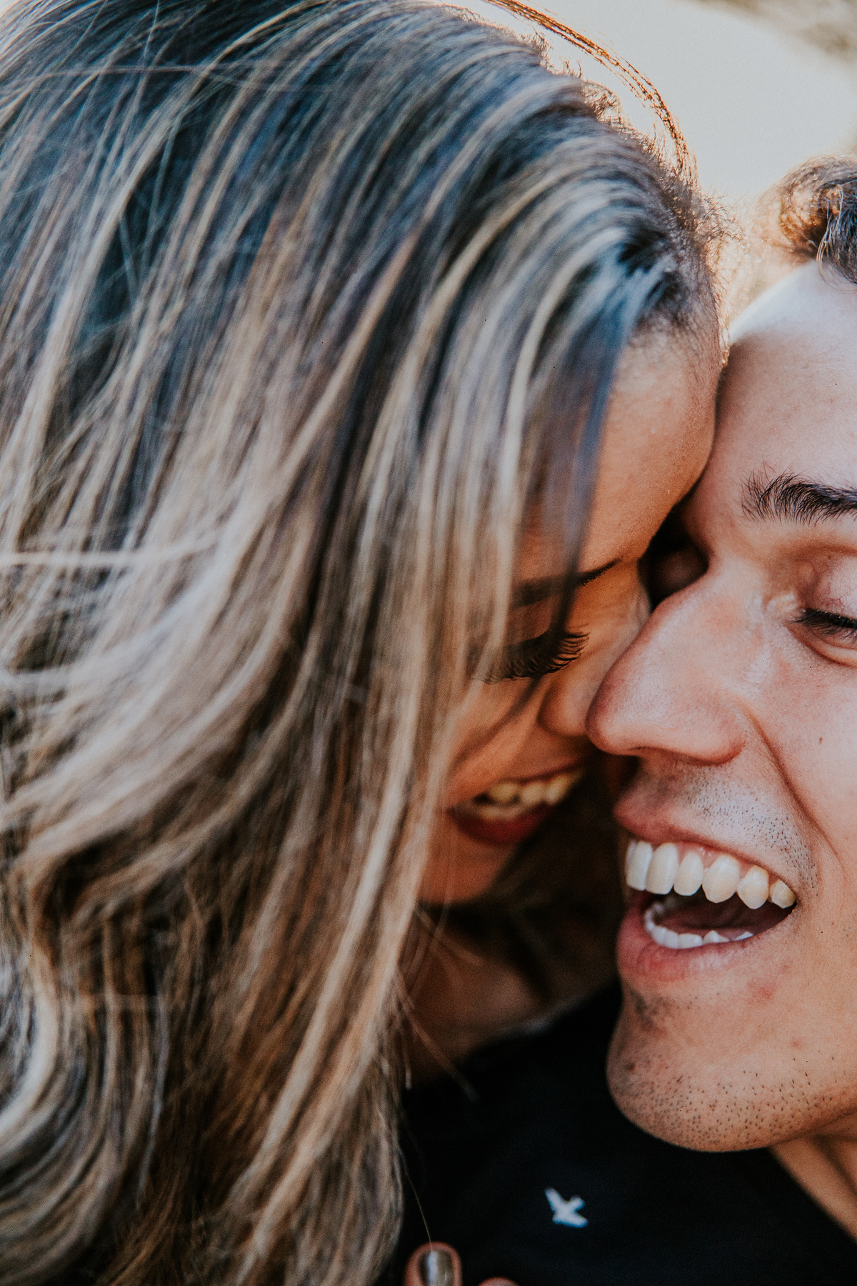 Fotografia espontânea de casal no por do sol no qual os dois estão sorrindo um para o outro