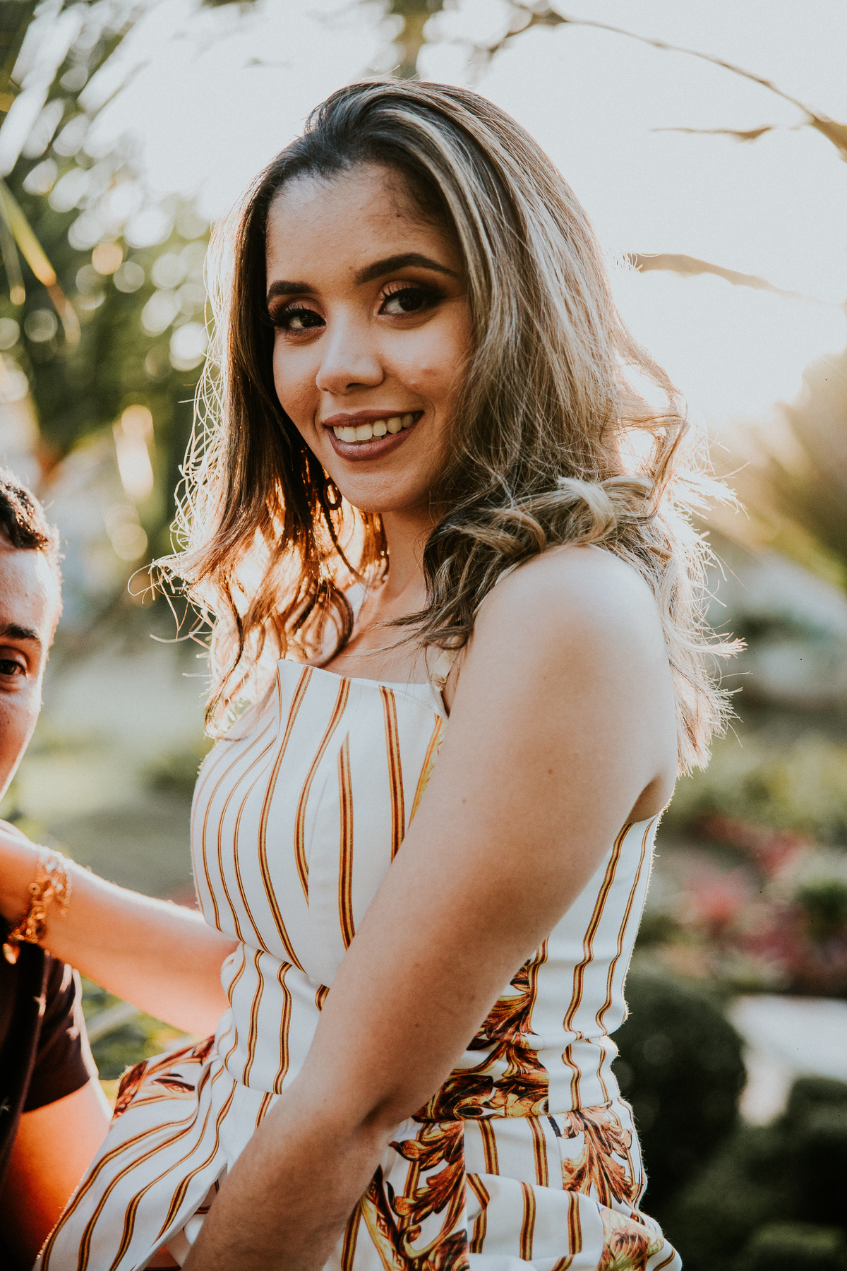 Retrato feminino no qual a noiva está sorrindo para a camera em um retrato no por do sol
