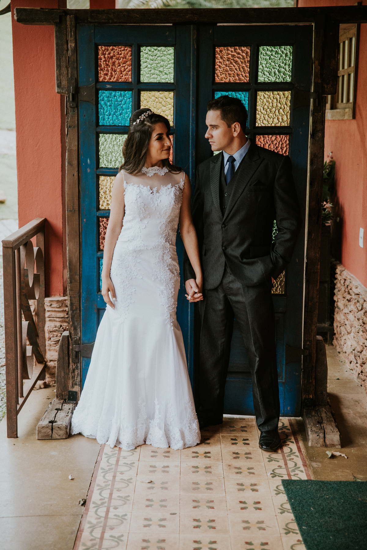 Fotografia de pós casamento rustico no qual os noivos estão de mãos dadas na frente de uma porta de vidro para a entrada da noiva na fazenda arraial velho