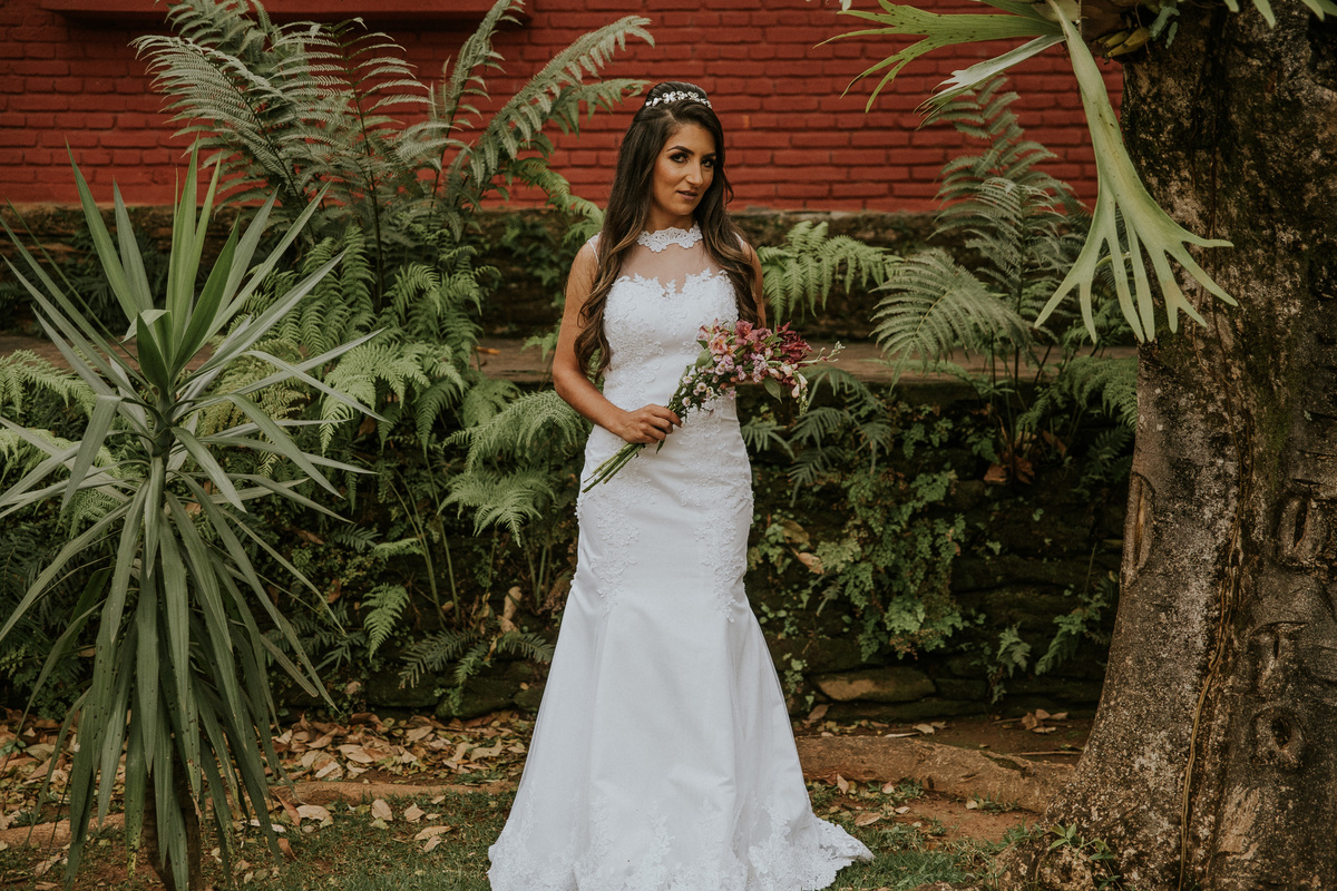 fotografia de oós casamento fazenda arraial velho em sabara no qual a noiva está segurando o buque de noiva e mostrando seu vestido de noiva estilo sereia