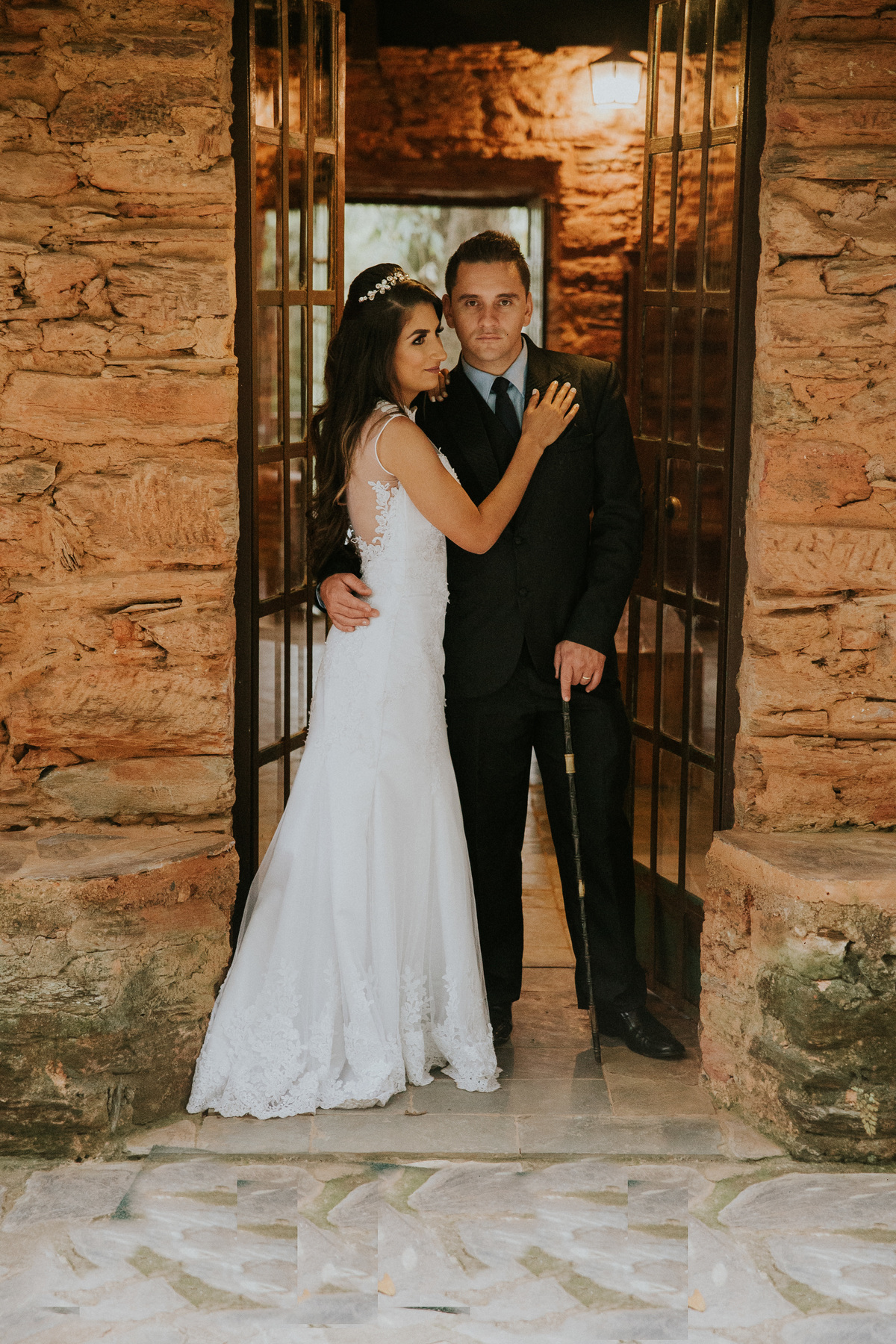 noivos se abraçando durante as fotos de pós casamento na fazenda arraial velho em sabara no qual o noivo está usando uma bengala para compor a fotografia 