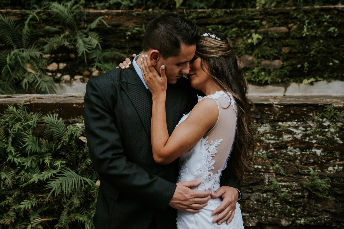 Fotografia de pós casamento na fazenda arraial velho no qual os noivos estão se abraçando em frente a um muro de pedras rustico 
