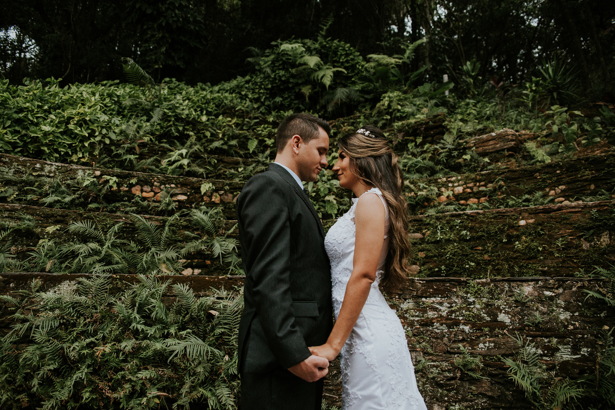 Fotografia de pós casamento na fazenda arraial velho no qual os noivos estão se abraçando em frente a um muro de pedras rustico 
