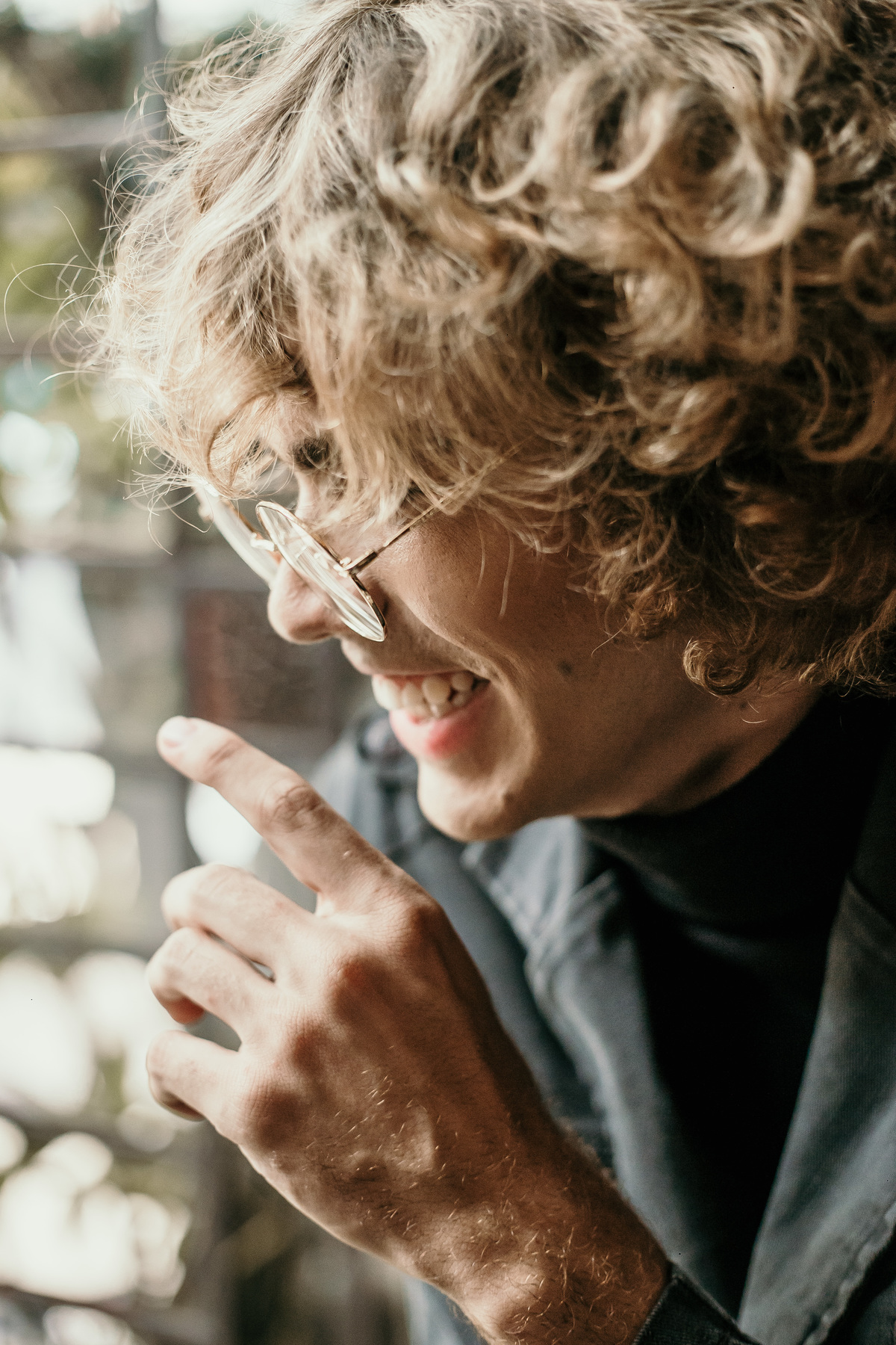 ensaio masculino tumblr no qual o modelo está sorrindo e olhando pela janela enquanto toma um café em uma cafeteria na Savassi