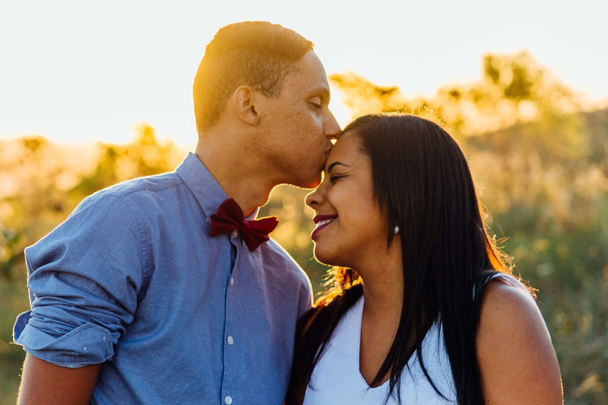 fotos no por do sol de recem casados, eles estão sorrindo e abraçados olhando um para o outro com um olhar apaixonado, beijo na testa