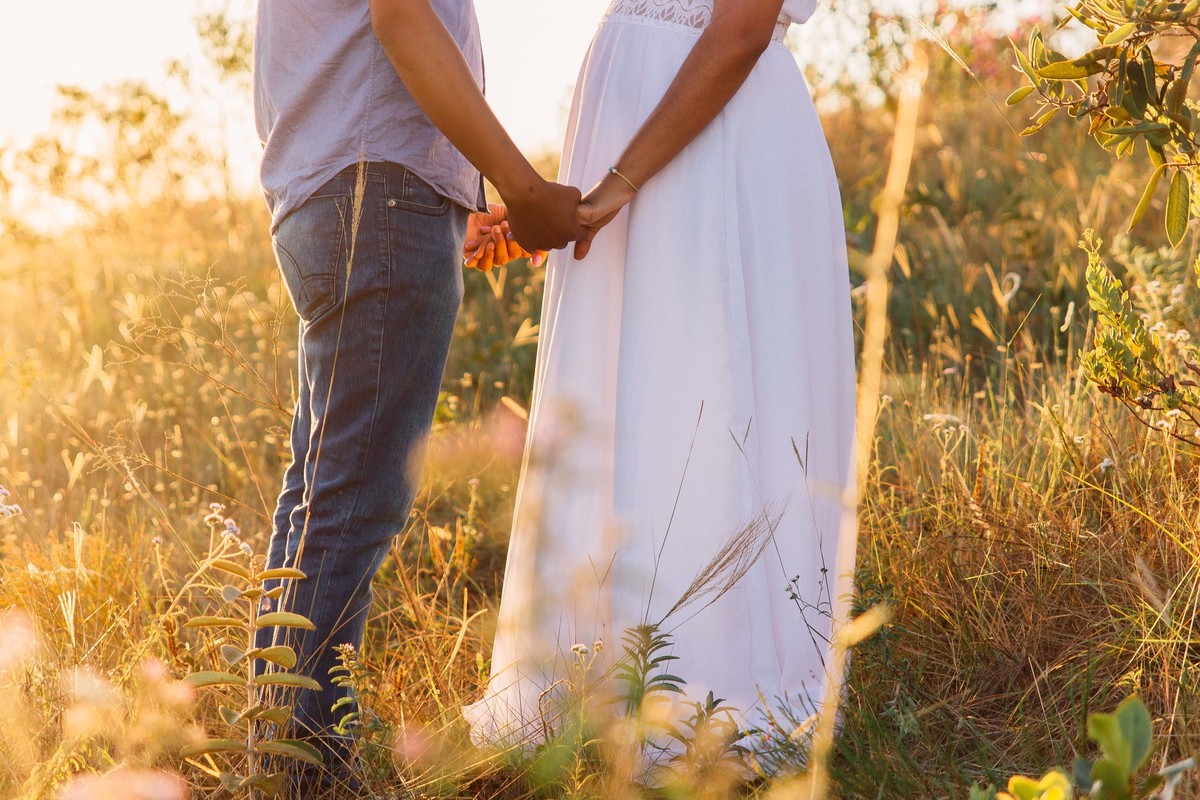 ensaio fotografico no por do sol, os noivos estão de mãos dadas olhando um para o outro