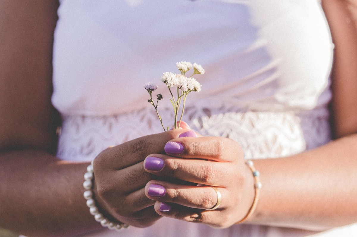 fotos no por do sol de recem casados, na frente de uma igreja azul, noiva com vestido branco e segurando um buque alternativo