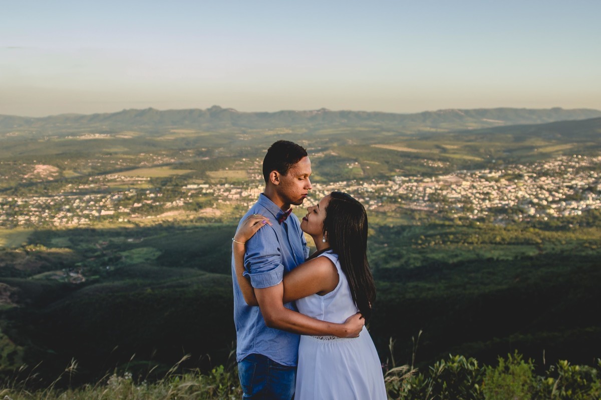 fotos no por do sol de recem casados, na frente de uma igreja azul, noiva com vestido branco e o noivo com blusa social e gravata borboleta, noivos se abraçando e olhando um para o outro