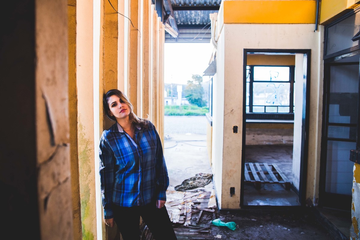 Ensaio fotografico no por do sol, mulher usando roupas masculinas e aboatoando a camisa, fotos feitas em Juatuba em posto abandonado, ensaio com blusa xadrez e calça jeans