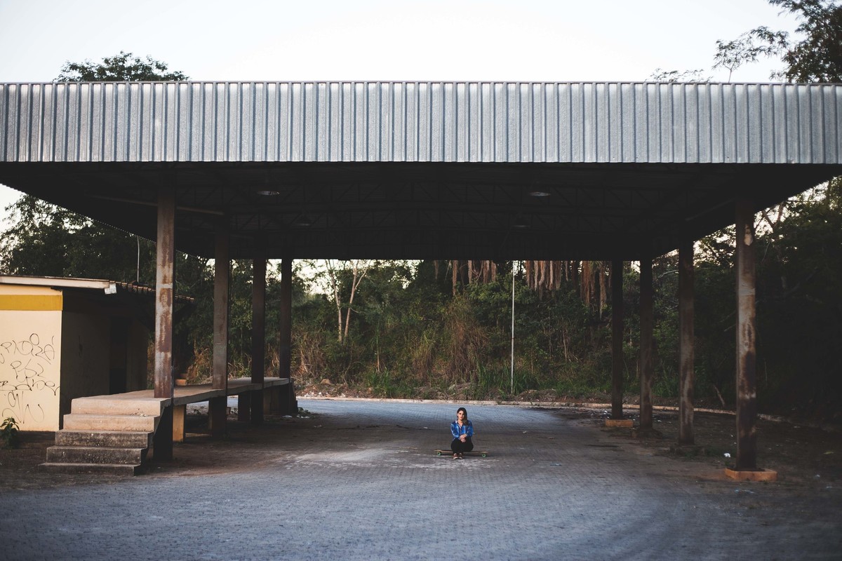 Ensaio fotografico no por do sol, mulher usando roupas masculinas e aboatoando a camisa, fotos feitas em Juatuba em posto abandonado