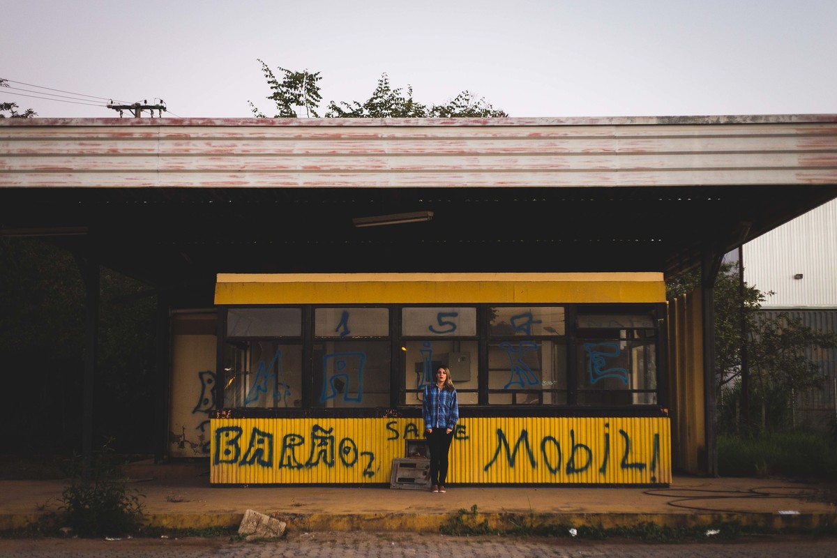 Ensaio fotografico no por do sol, mulher usando roupas masculinas e aboatoando a camisa, fotos feitas em Juatuba em posto abandonado,