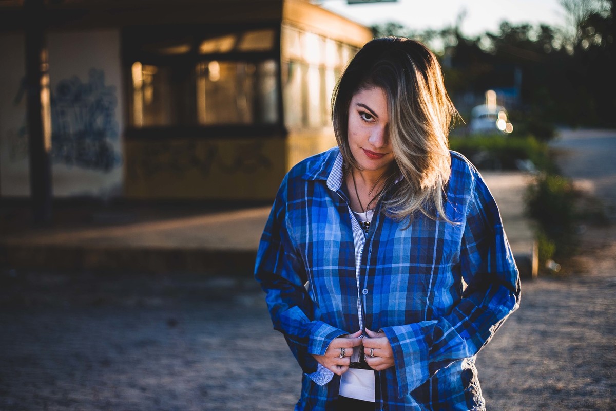 Ensaio fotografico no por do sol, mulher usando roupas masculinas e aboatoando a camisa, fotos feitas em Juatuba em posto abandonado