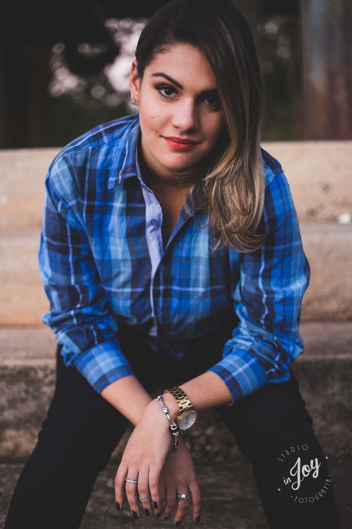 Ensaio fotografico no por do sol, mulher usando roupas masculinas e aboatoando a camisa, fotos feitas em Juatuba em posto abandonado, modelo sentada em uma escada com os braços cruzados
