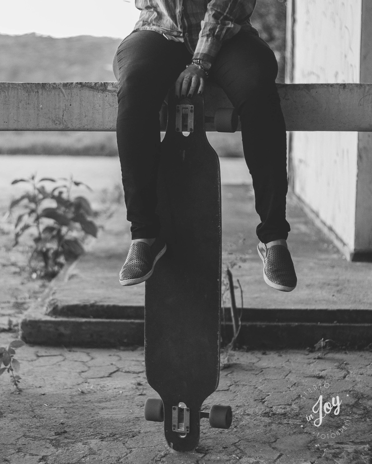 Ensaio fotografico no por do sol, mulher usando roupas masculinas e aboatoando a camisa, fotos feitas em Juatuba em posto abandonado, modelo sentada numa pilastra segurando o skate, foto em preto e branco