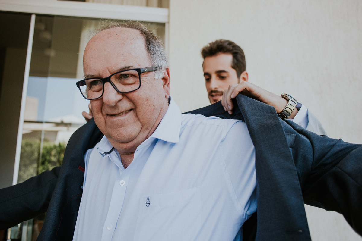 Fotografia do dia noivo no qual o noivo esta se arrumando em casa juntamente com amigos e o pai no condomínio Mont Serrat em Betim