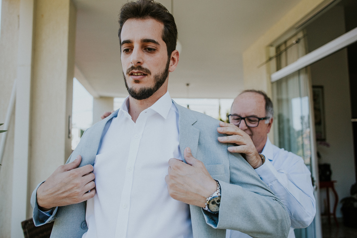 Fotografia do dia noivo no qual o noivo esta se arrumando em casa juntamente com amigos e o pai no condomínio Mont Serrat em Betim